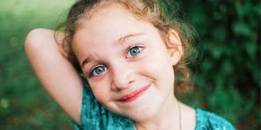A young bright-eyed girl outside, capturing the 'growth mindset' and curiosity that experts say are more important than academic performance.