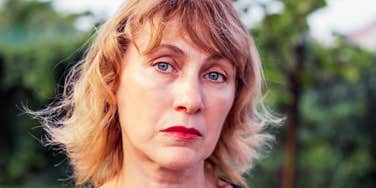 A portrait of a middle-aged woman with blonde hair and a pensive, sad expression, illustrating the complex internal loneliness that can persist even when life appears busy and full.