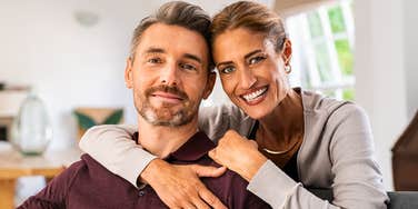 A happy 50-year-old couple sitting together at home, illustrating the 'quiet connection' and low-conflict communication habits that increase marital satisfaction in mid-life.