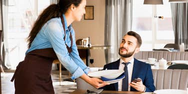 server clearing stacked plates from customer trying to help