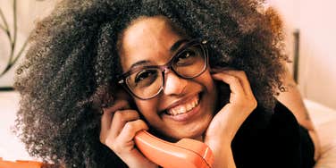 Woman smiling while talking on the phone, illustrating personality traits of people who prefer calling over texting