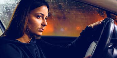 serious woman driving a car at night in the rain trying to focus