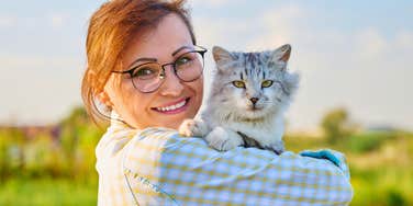 high-value woman who loves animals snuggling a cat outside