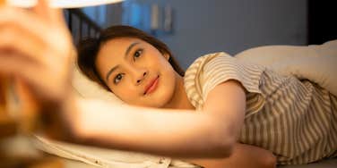 smiling woman looking forward to bedtime shutting off the light