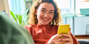 happy woman at home looking up a restaurant menu on her phone
