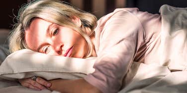 woman in bed sleeping too much and looking sad over small things