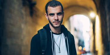 Man with personality traits that make him unattractive standing in an arch