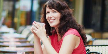 A woman enjoying a peaceful meal alone at an outdoor cafe, illustrating the quiet confidence and emotional healing that follows a difficult breakup.