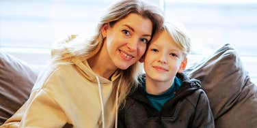 A portrait of a stepparent and child sharing a cozy moment at home, representing the 'secondary attachment' and emotional patience required in step-parenting.