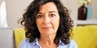 A stoic mature woman sitting at her office desk, representing the quiet exhaustion and internal reflection that often precedes the decision to leave a long-term role.