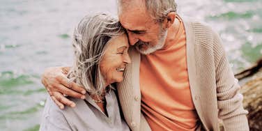 A senior couple sharing a romantic moment by the sea, illustrating the deep emotional connection and empathy that sustain long-term relationships through life's challenges.
