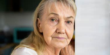 A woman looking pained and thoughtful, illustrating the difficult experience of reconciling a fractured relationship with a parent later in life.