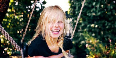 A happy girl playing outside, capturing the 'autonomy' and resilience developed through unstructured play and strong parent-child connection.