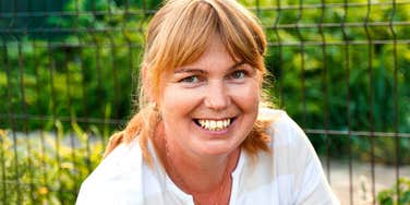 A smiling mature woman in a striped shirt looking relaxed and content, illustrating the 'internal shifts' and emotional resilience experts recommend for finding happiness as you age.