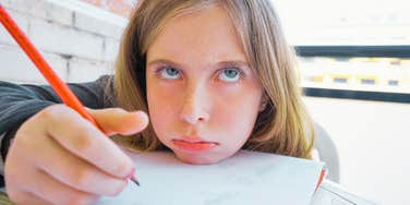 A bored student sitting at a table, representing the heavy silence and tension in a classroom after a teacher's unexpected question.