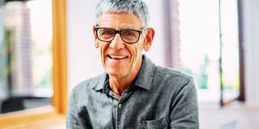 Confident Baby Boomer man smiling at the camera, illustrating phrases or habits that younger generations often roll their eyes at