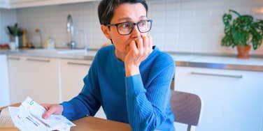 woman financially stressed out holding unpaid bills