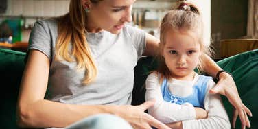 Mother trying to talk to her daughter, who sits with crossed arms and an angry expression, illustrating modern parental challenges. 