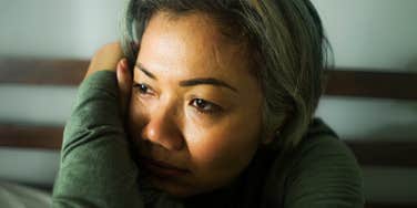 A mature woman with grey hair looking distant and detached, illustrating the 'subtle signs' of dissociation and the difference between stress and a freeze response.