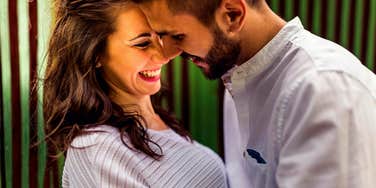 A man leaning into a woman in a cute, spontaneous moment, illustrating the 'micro-bids' for connection that sustain long-term marriages.