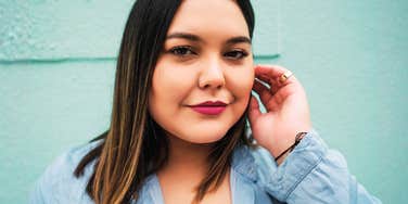 A confident young plus-size woman looking directly at the camera with a calm and resolute expression, illustrating the 'self-possession' required to maintain firm personal boundaries.