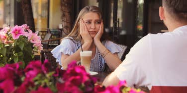bored woman sitting on date outside with man at table