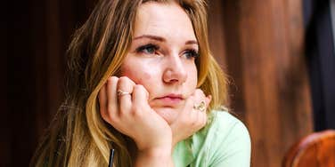 A lonely young woman resting at a cafe table; a visual representation of the difficult journey toward self-awareness and understanding the roots of social isolation.