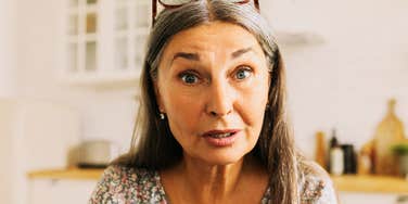 A beautiful Caucasian woman texting with raised eyebrows, illustrating 'affective misinterpretation' and the risks of sharing sensitive news via text.