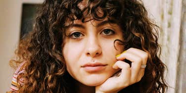 A portrait of an intelligent woman with curly hair maintaining steady eye contact; illustrating the "non-manipulative" psychological tricks and personality traits that help people achieve their goals.