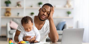 stressed dad sitting at table with baby in arms