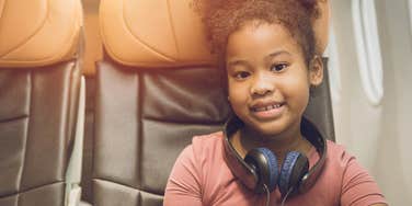 kid sitting alone in economy while her parents are in first class