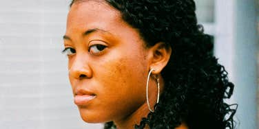 An angry woman looking over her shoulder with a look of betrayal, illustrating the 'medical gaslighting' and long-term diagnostic delay faced by rare disease patients.