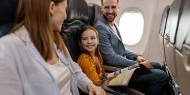 parents with young daughter smiling while sitting on plane