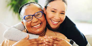 A smiling Gen X parent and her daughter sharing a close embrace; illustrating the deep bond and the complex emotional work Gen X families are doing in therapy today.