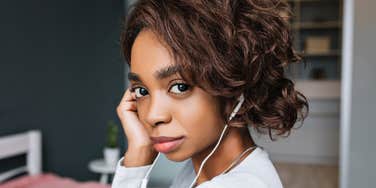 A close-up of a young girl with a pensive expression wearing headphones; illustrating the 'uncomfortably familiar' traits of quiet independence and emotional withdrawal found in adults with difficult childhoods.