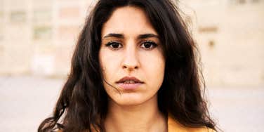 A close-up portrait of a woman with a somber, steady gaze; illustrating the internal strength and quiet intensity often found in those navigating the long-term effects of childhood emotional unavailability.