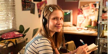 A portrait of a woman in nineties-style clothing studying with a portable music player, capturing the unique and sometimes cringeworthy charm of 90s youth culture.