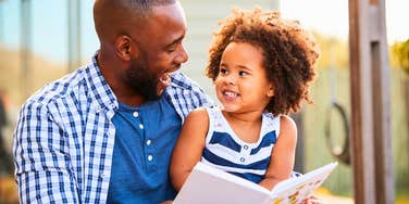 dad reading to his intelligent daughter encouraging her