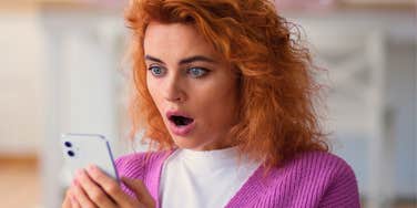 highly intelligent woman shocked looking at her phone