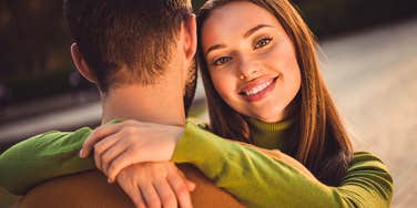 highly intelligent wife hugging her husband and smiling