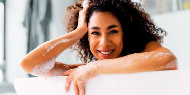 A relaxed woman leaning over a bathtub; a visual representation of 'passive heating' research showing how hot baths can improve health markers similarly to moderate exercise.