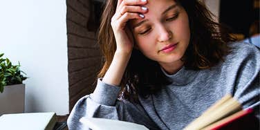 Young woman reading a book outdoors in a cafe 