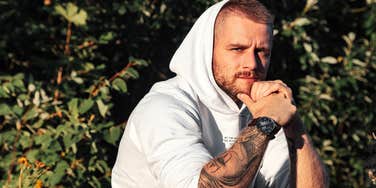 Man who was constantly grounded as a kid looks serious with tattoos and a hoodie
