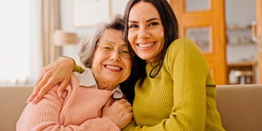 millennial woman hugging her boomer mother smiling