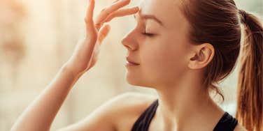 Woman managing chronic pain touching her forehead peacefully 