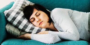 A woman sleeping comfortably on a sofa during the day; a visual of the restorative napping habits that studies show enhance mental clarity differently than overnight sleep.