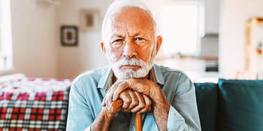 An elderly man sitting with a cane, illustrating the subtle mobility changes that doctors warn may be a hidden health risk rather than normal aging.
