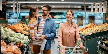 parents grocery shopping with young daughter 