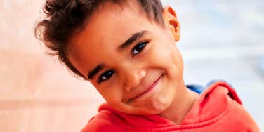A confident young boy with brown hair smiles thoughtfully, embodying the independence and self-esteem gained from the rare parenting phrases mentioned in the guide.