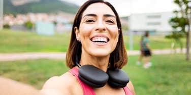 A confident middle-aged woman in sportswear smiling for a phone selfie while training outside; illustrating the positive lifestyle changes and newfound independence typical of those thriving after divorce.